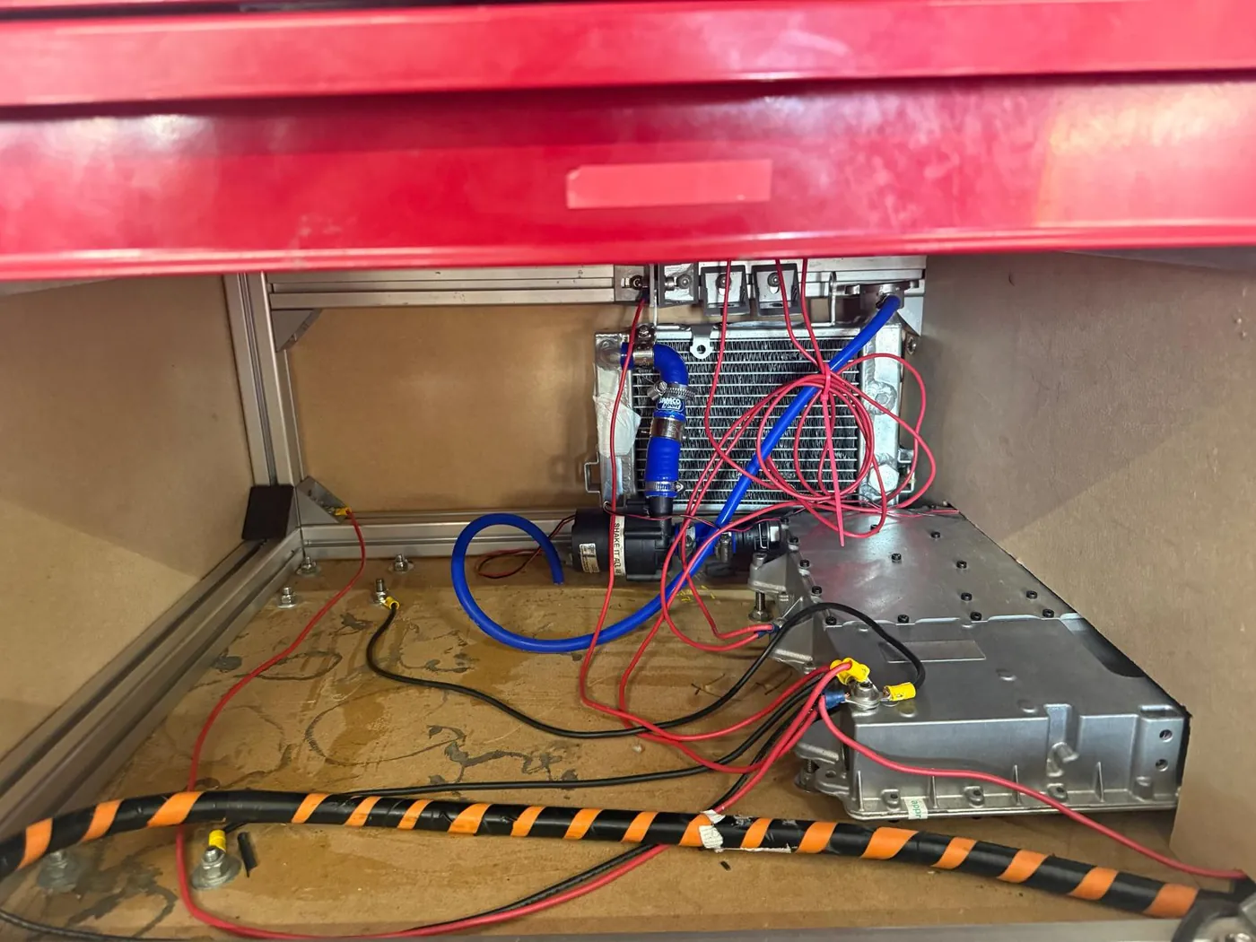 Inside the trolley: the charger, the radiator and coolant lines of the cooling loop, high-voltage cabling in spiral wrap, and the extrusion base frame